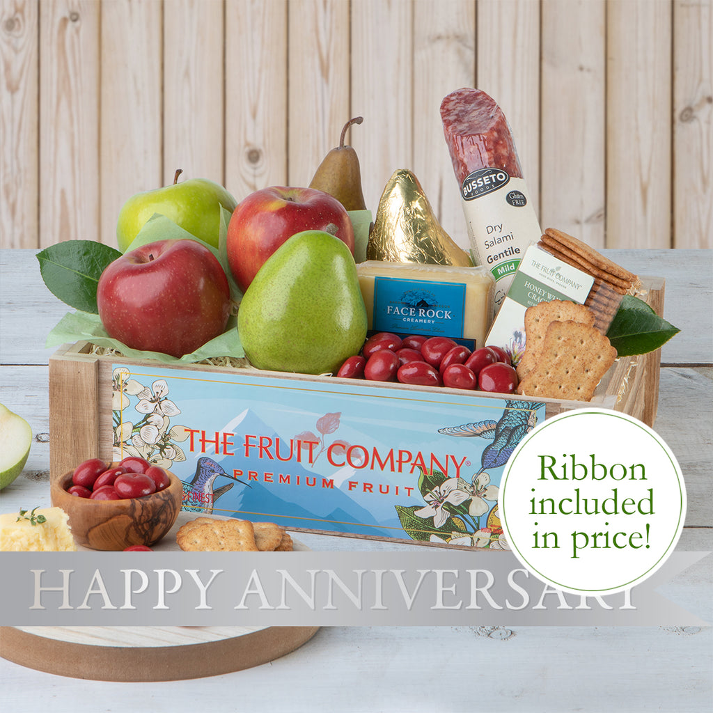 Happy Anniversary gift crate with all its contents beautifully arranged The Happy Anniversary gift crate with the contents unpacked and a lovely bow tied on it Anniversary basket with fruits, cheese, crackers, and meats