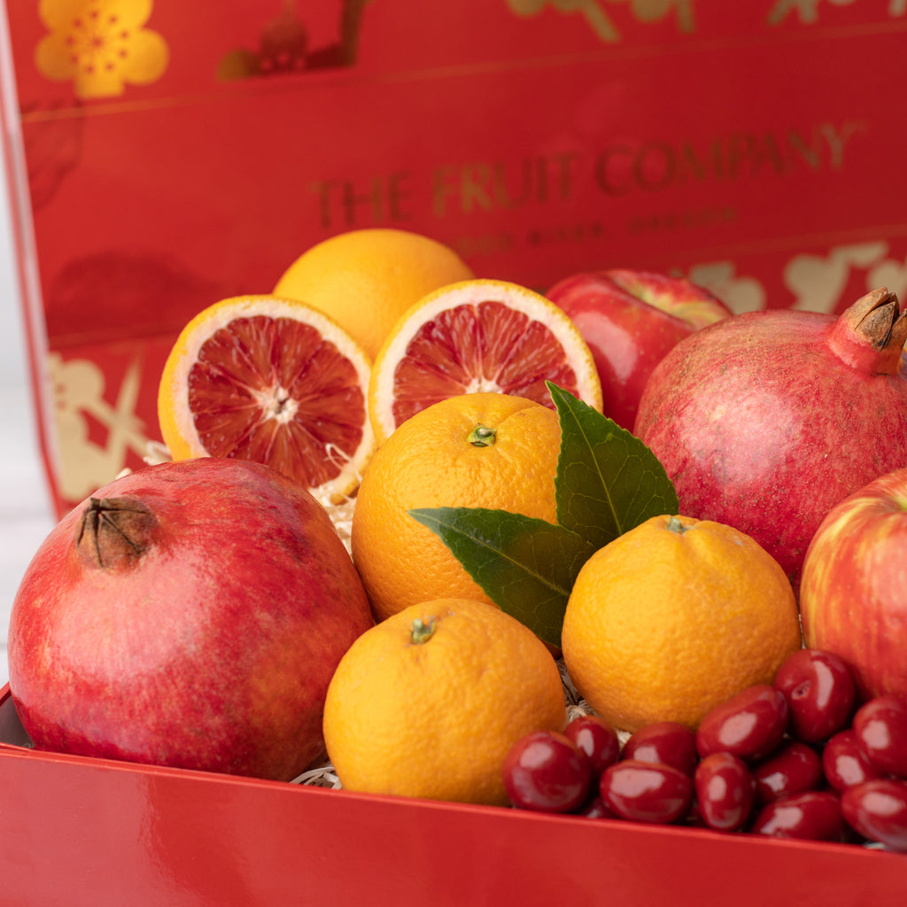 Pomegranates, blood oranges, and chocolate covered Cherries Dark chocolate blood orange caramel Oranges, apples, and pomegranates Delicious, juicy red apple Close shot of citrus, apples, and pomegranate Gorgeous red and gold Lunar New Year gift box with all of its contents