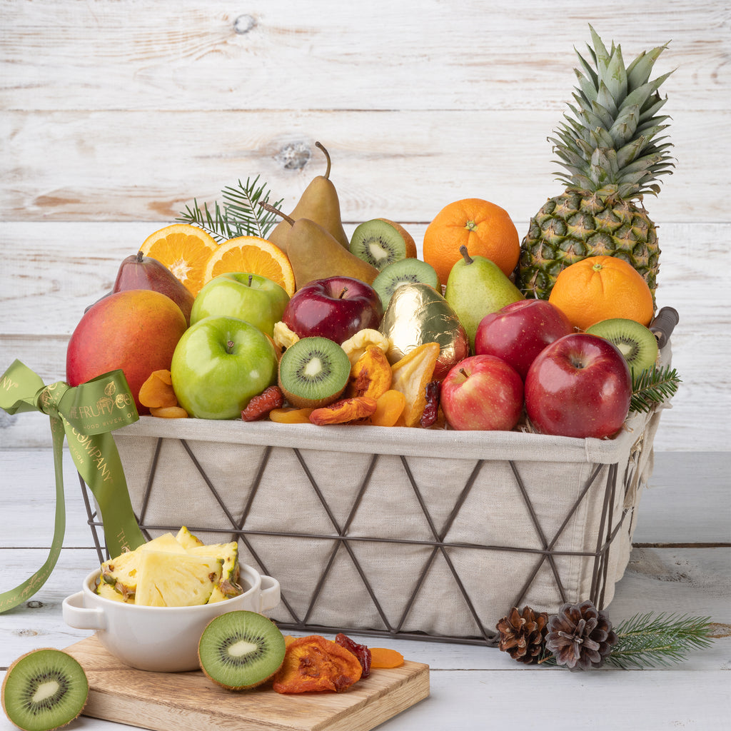 Shiny green apple and mango in a gift basket Aerial shot of tropical fruit basket and cut fruit Close up shot of kiwi, apples, oranges and gold wrapped pear Fresh kiwi, apples, oranges, a gold wrapped pear and dried fruit Close up shot of mixed whole