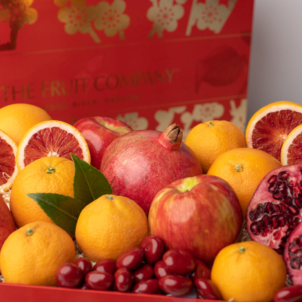 Pomegranates, blood oranges, and chocolate covered Cherries Dark chocolate blood orange caramel Oranges, apples, and pomegranates Delicious, juicy red apple Close shot of citrus, apples, and pomegranate Gorgeous red and gold Lunar New Year gift box with all of its contents