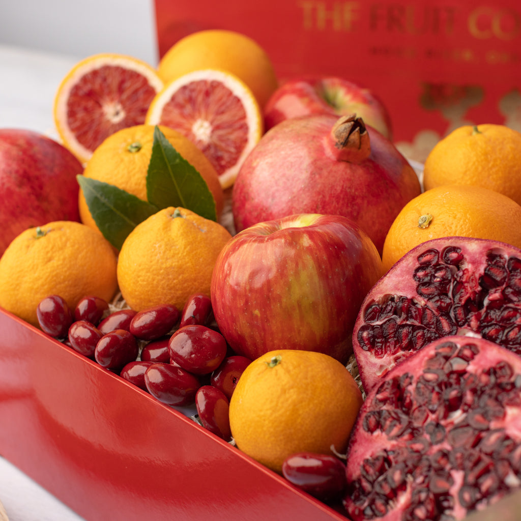 Pomegranates, blood oranges, and chocolate covered Cherries Dark chocolate blood orange caramel Oranges, apples, and pomegranates Delicious, juicy red apple Close shot of citrus, apples, and pomegranate Gorgeous red and gold Lunar New Year gift box with all of its contents