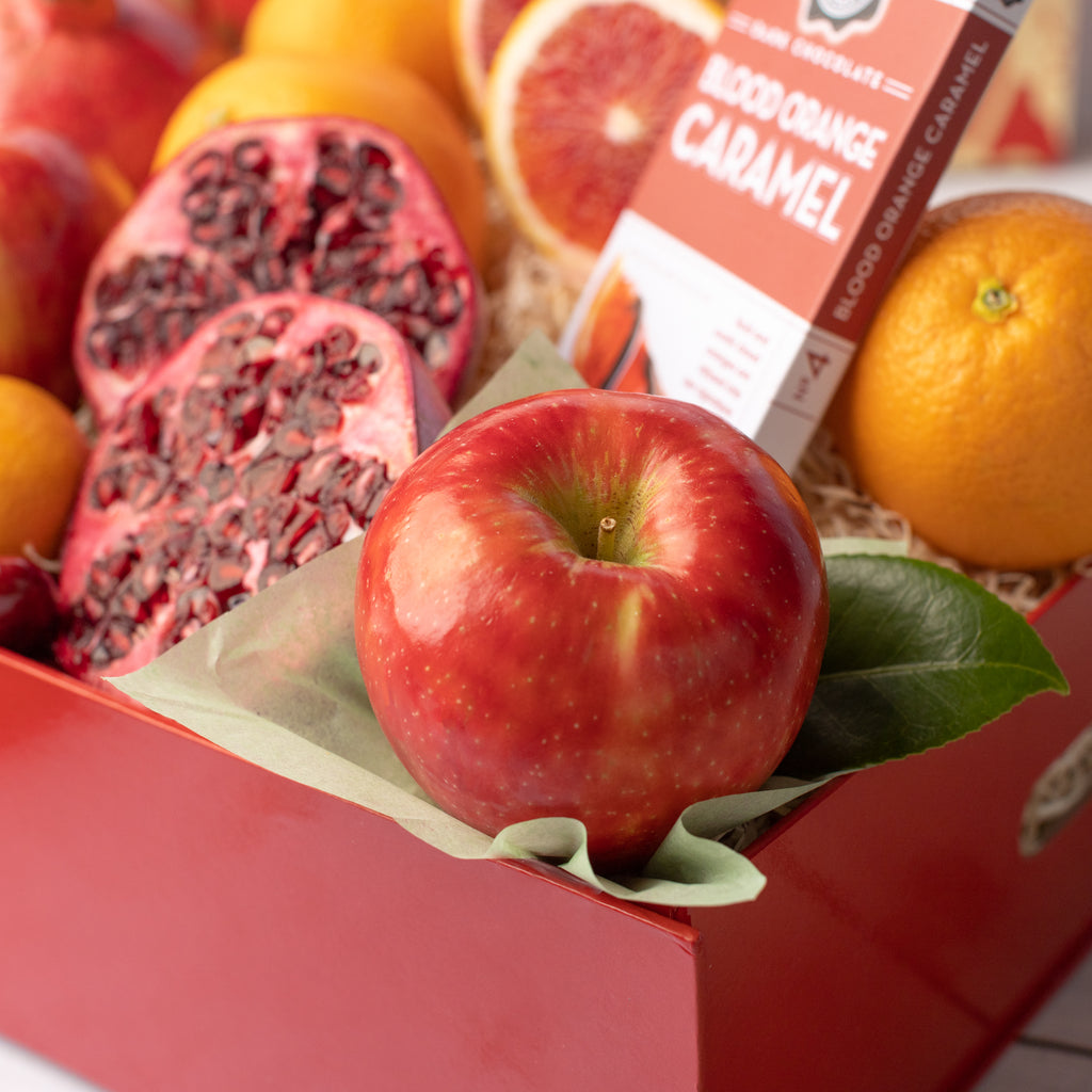 Pomegranates, blood oranges, and chocolate covered Cherries Dark chocolate blood orange caramel Oranges, apples, and pomegranates Delicious, juicy red apple Close shot of citrus, apples, and pomegranate Gorgeous red and gold Lunar New Year gift box with all of its contents